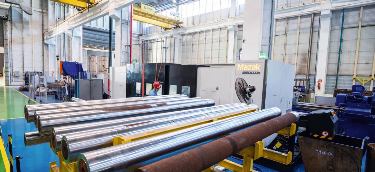 Photo of freshly machined steel rolls are staged and ready for quality inspection, with a Mazak CNC turning center in the background.
