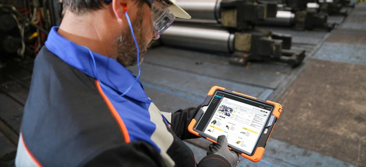  Maintenance engineer holding a tablet displaying an HMI screen with real-time condition monitoring data of the rolling mill, evaluating equipment status and performance to ensure optimal operation and timely maintenance.