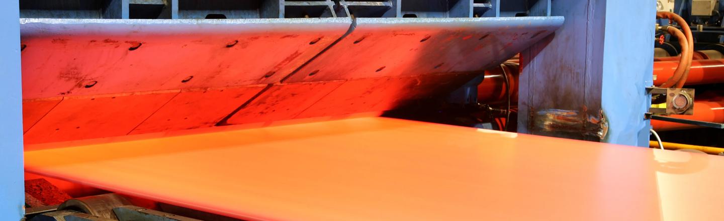 Hot steel strip exiting the roll gap with excellent contour and flatness, controlled by the Contour and Flatness Optimizer system that uses advanced algorithms and online material flow modeling to enhance steel strip quality and production efficiency.