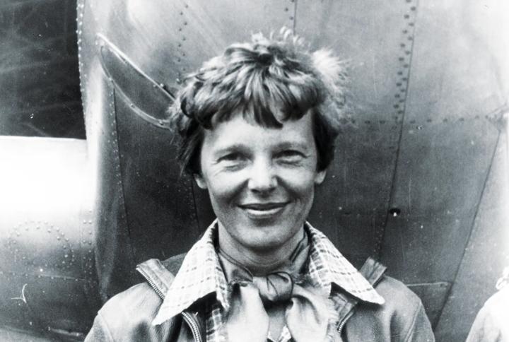 Amelia Earhart standing under nose of her Lockheed Model 10-E Electra