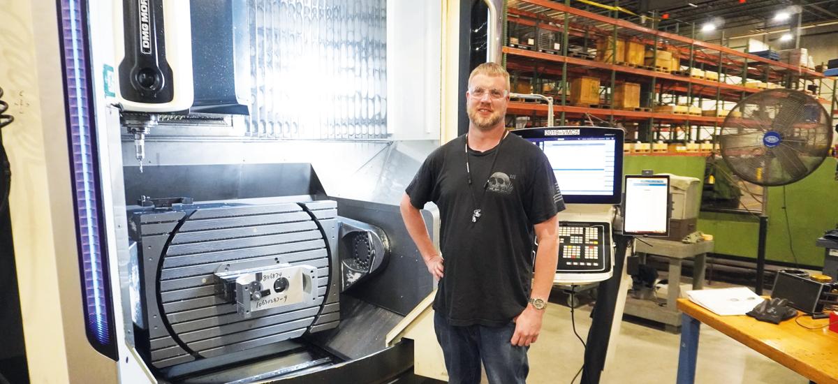 Aaron Kaliszewsky is working on a roller holder. As the doors of his 5-axis CNC machine are currently open, the rotating and tilting table is fully visible.