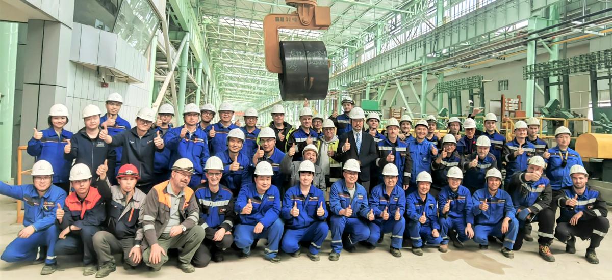 河北省にあるプラントで、No. 2 Arvedi ESPのファーストコイルを背景にしたプライメタルズ テクノロジーズ チーム