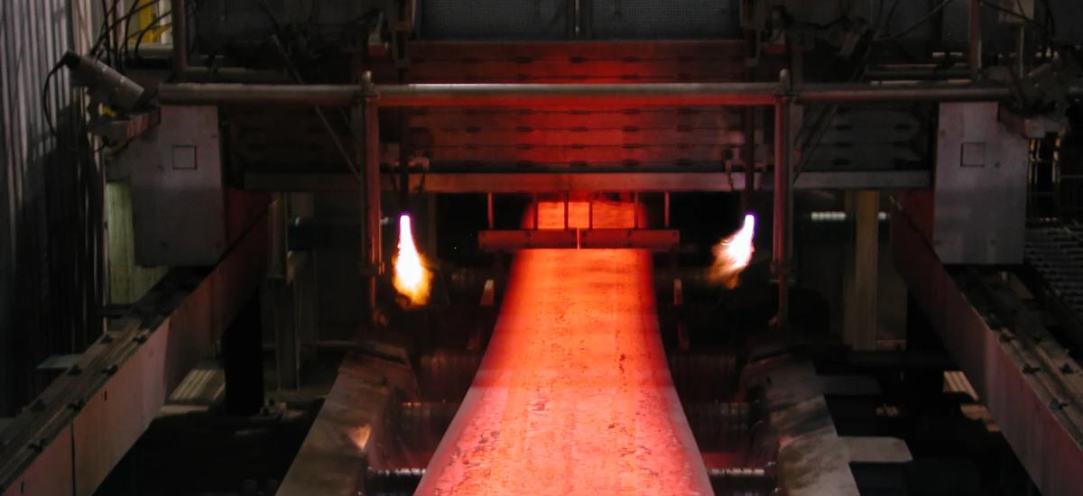 Hot steel slab moving through caster rolls during continuous casting