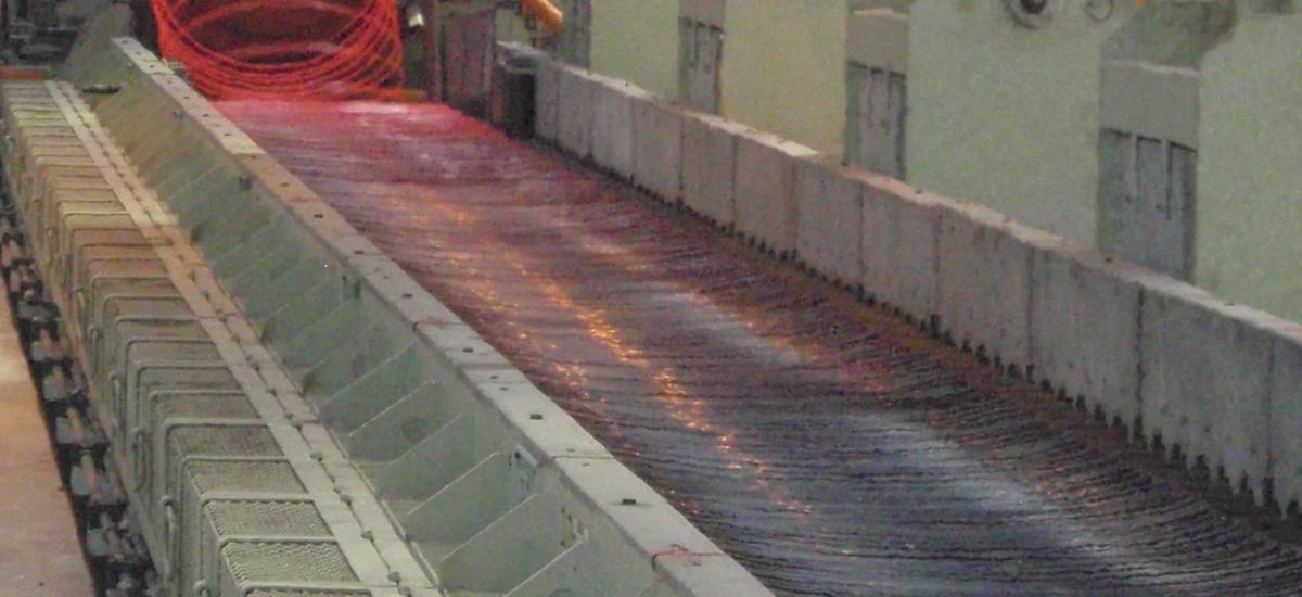 Morgan Stelmor Cooling Conveyor operating with Optimesh system from Primetals Technologies beneath nozzle deck. Optimesh ensures cooling uniformity for high carbon products in fast cooling mode. The system will be installed in a wire-rod outlet of Zenith Steel in China.