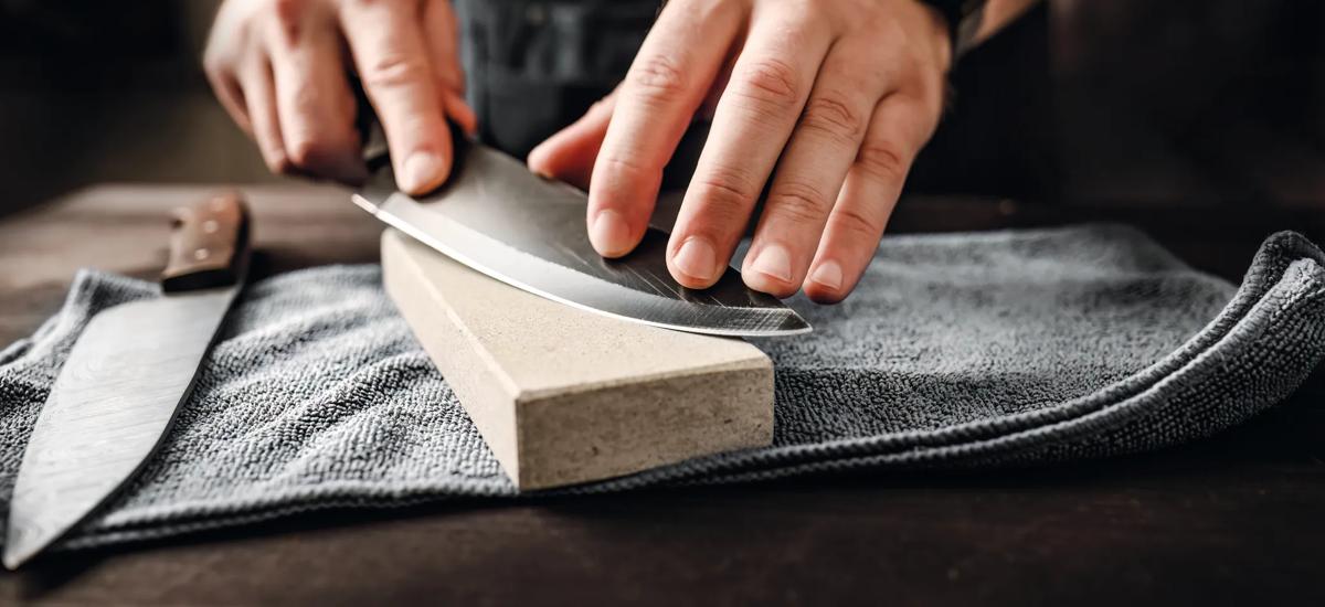 A man is sharpening a knife on a sharpening block.
