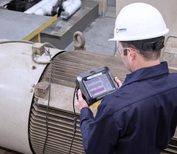 Technician performing route-based vibration analysis as part of predictive maintenance to assess steel plant equipment health.