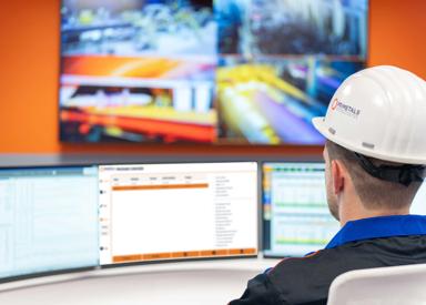 Operator monitoring continuous casting processes on multiple screens in a steel plant control room.