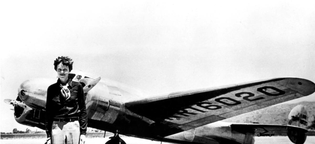 Amelia Earhart standing in front of her aircraft, full height.